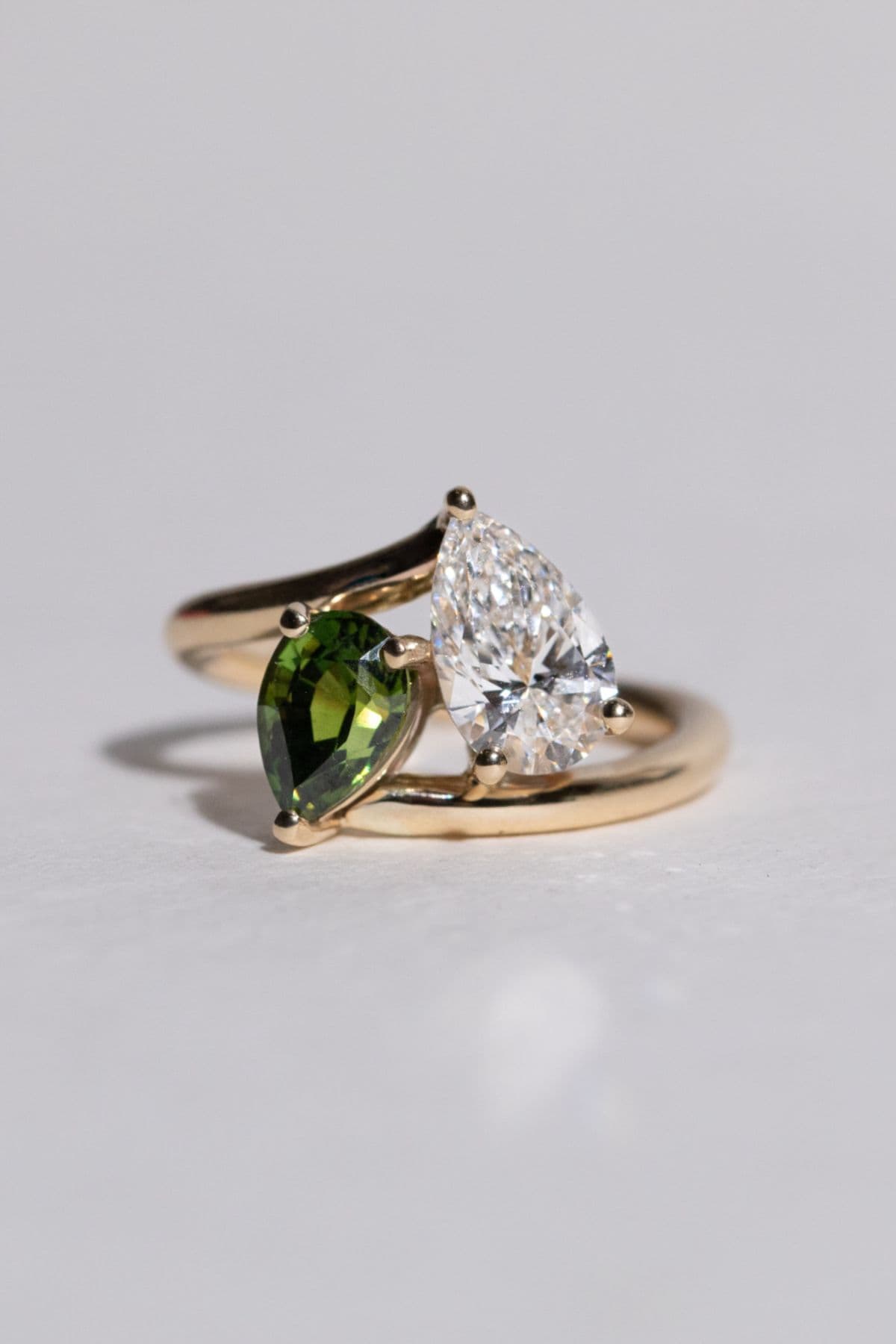 Toi et moi ring with pear diamond and pear emerald in yellow gold bypass setting