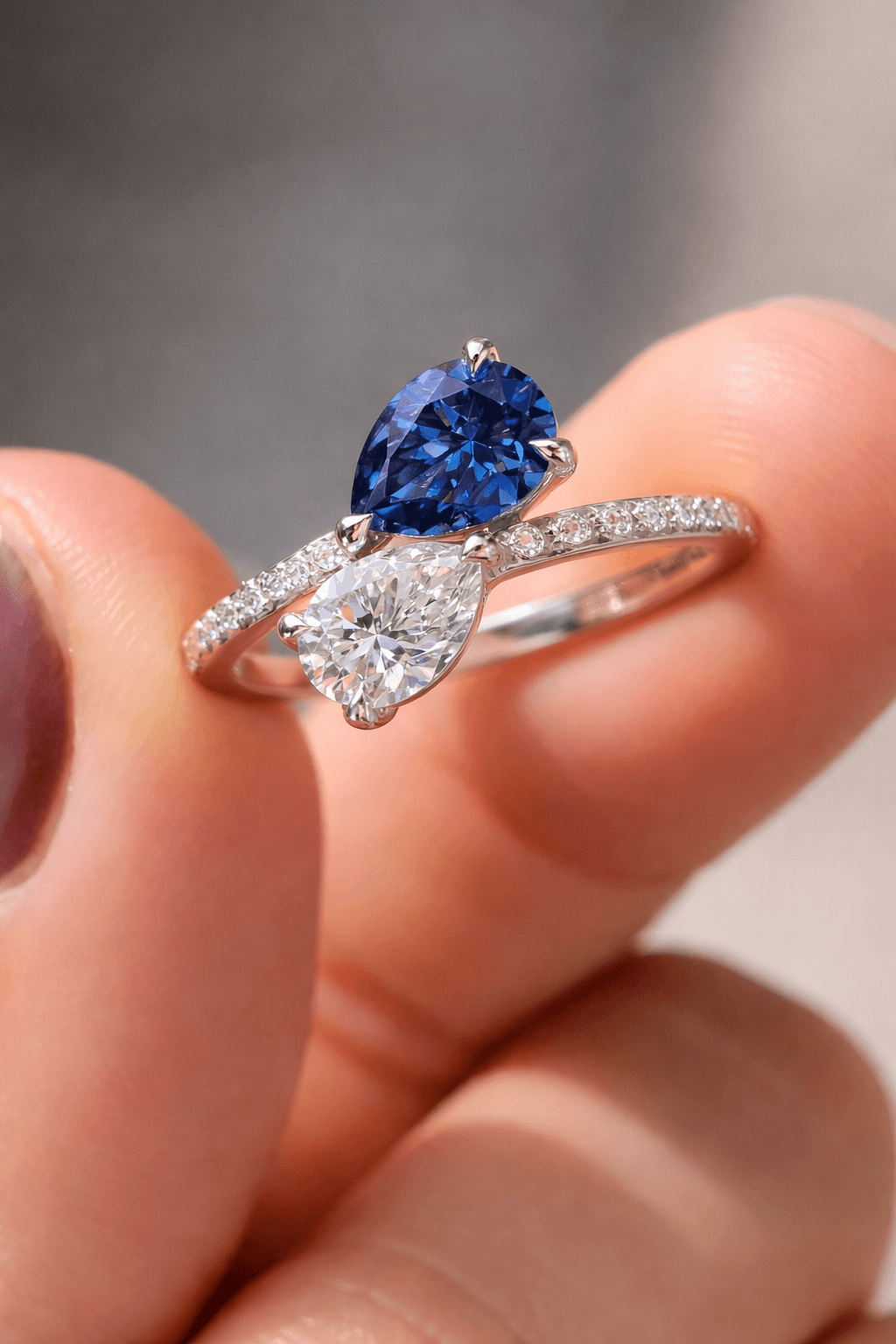 Toi et moi engagement ring with pear sapphire and pear diamond in platinum pavé bypass setting